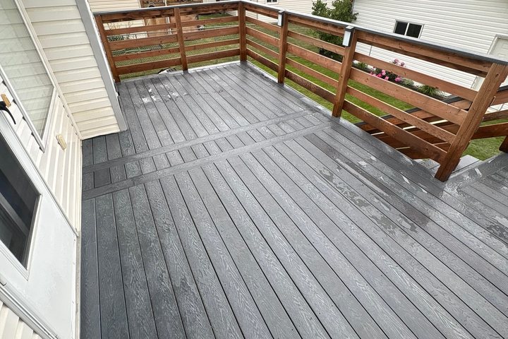 A deck laid in light grey recycled plastic lumber with a timber railing