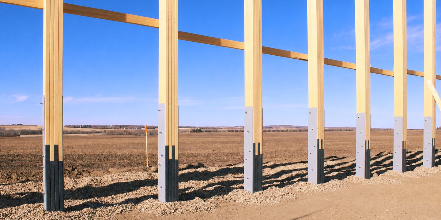 A row of Eco Column recycled plastic bases bolted to the timber posts of a new post-frame building