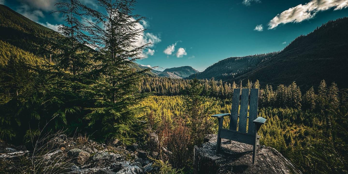 A recycled plastic Muskoka chair on a rock outcrop overlooking a forested valley