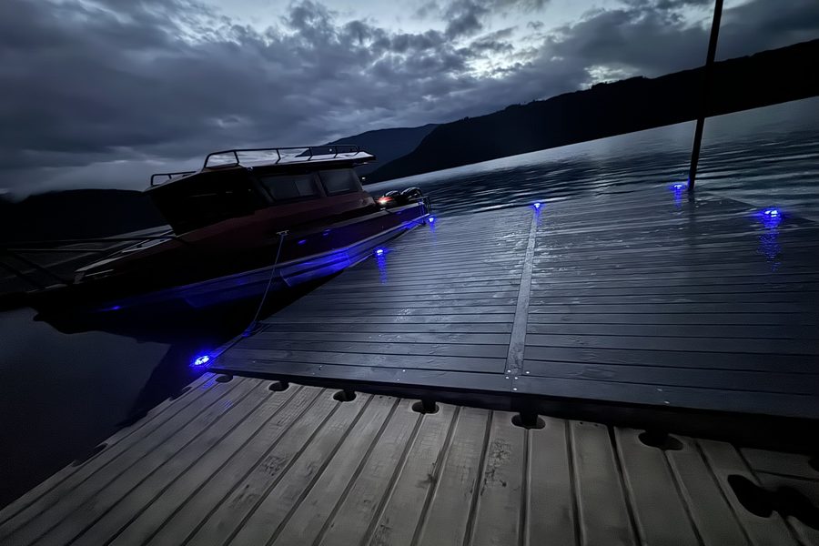 Dock decking at dusk, with low-level lights and a boat moored alongside