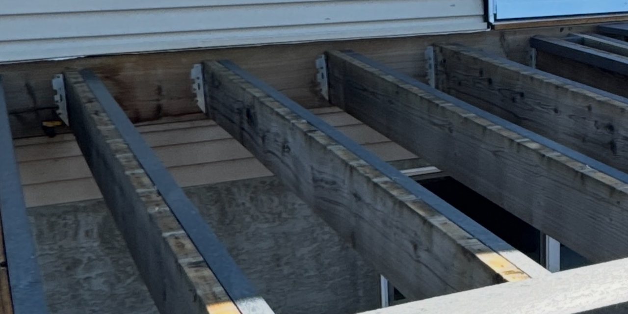 A deck part-laid in recycled plastic lumber with joists and the first boards visible